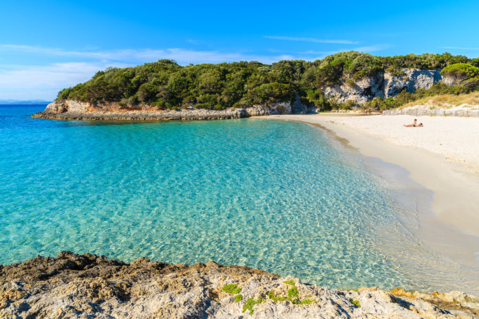 Unidentified young couple relaxing on beautiful Petit Sperone beach, Corsica island, France Corse