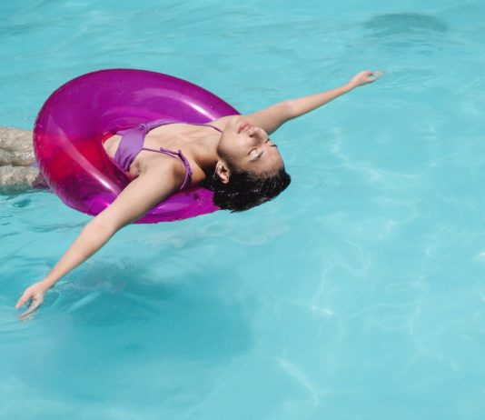 calm woman swimming in pool with swimming ring at resort